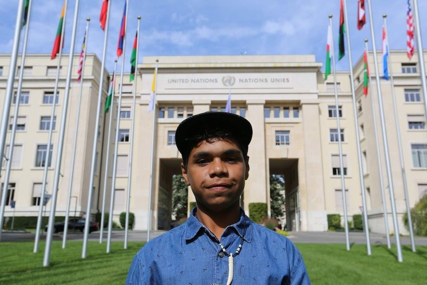 A young Indigenous boy smiles in front of a building