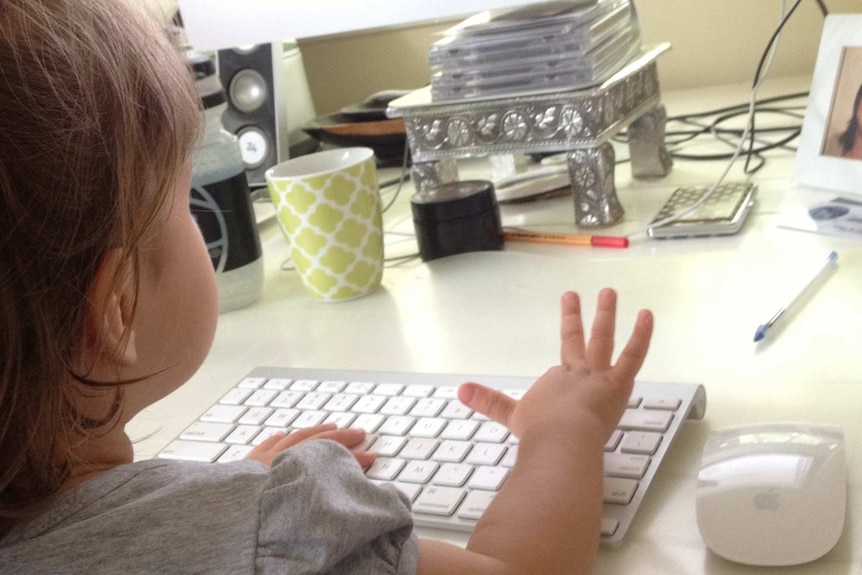 Lisa Schroder's child plays with the keyboard of her computer in her studio.