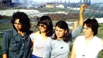 Four women stand outside the wire fence of the Port Kembla BHP steelworks.
