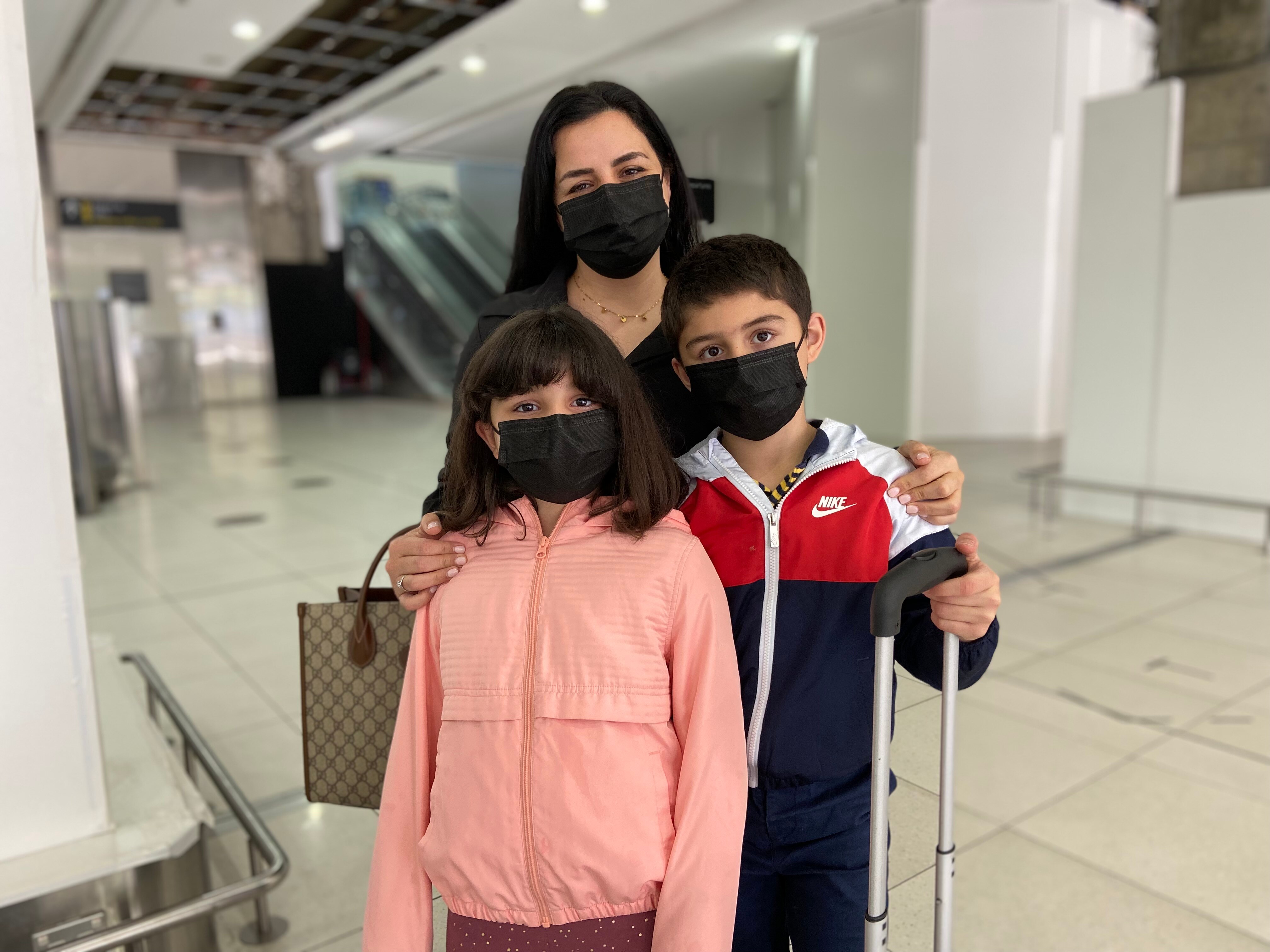 Woman girl and boy in black masks look to camera.