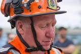 A man wearing an SES helmet looking down.