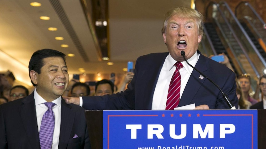 Donald Trump yells into a microphone with his hand on Setya Novanto's shoulder during an election event in New York.