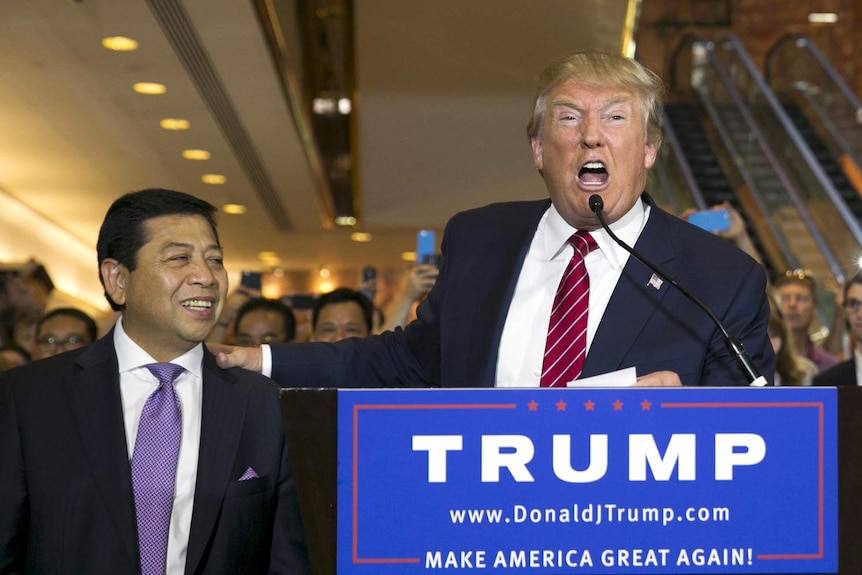 Donald Trump yells into a microphone with his hand on Setya Novanto's shoulder during an election event in New York.