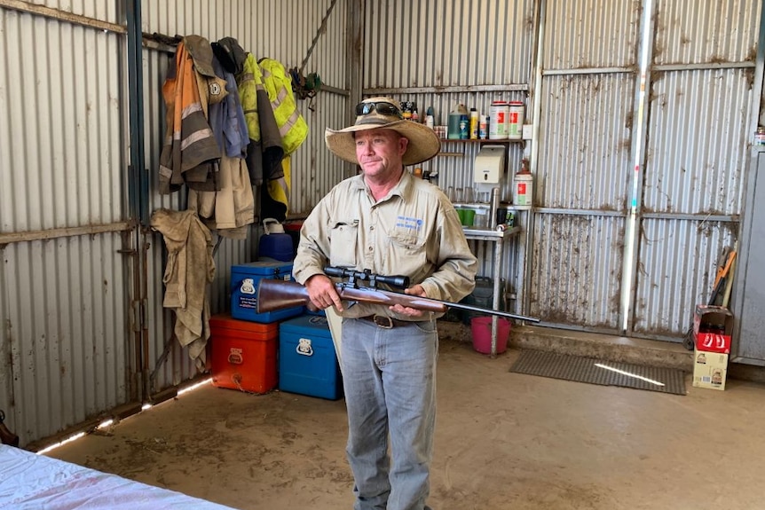 Michael Dwan holds a gun, standing in his shed.