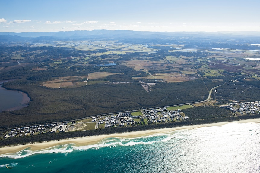 An aerial image of land near the coast with a mix of housing, forest and farmland