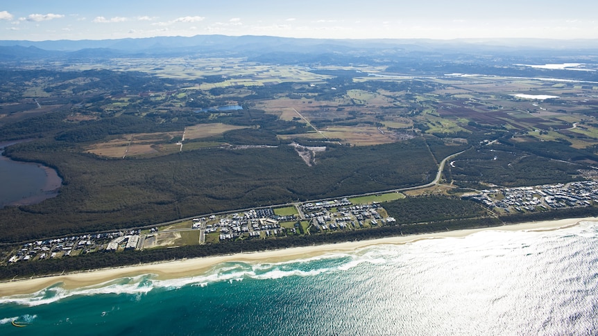 An aerial image of land near the coast with a mix of housing, forest and farmland