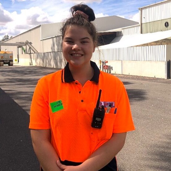 a girl wearing a fluro shirt smiles at the camera in front of a big building