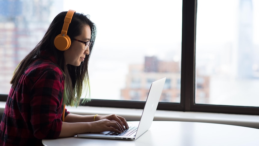 Woman wearing headphones working on laptop computer