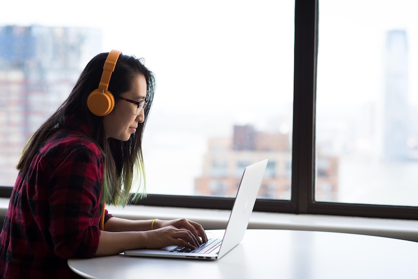 Woman wearing headphones working on laptop computer