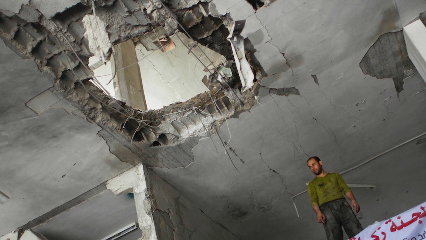 A Palestinian man stands in a destroyed building following an Israeli air strike.