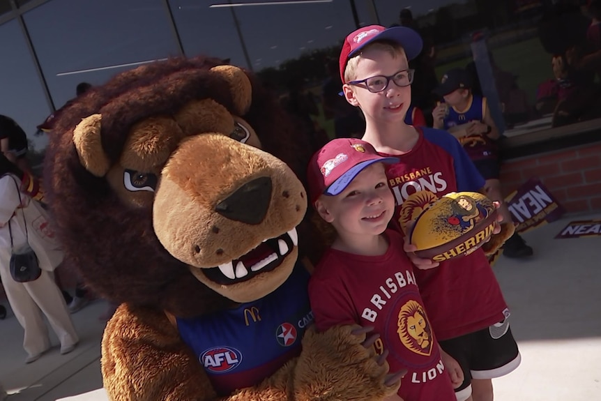 A lion mascot takes a photo with two young fans