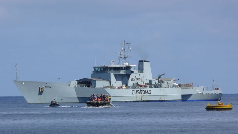 A Customs boat sits off the coast of Christmas Island after escorting a boat of asylum seekers