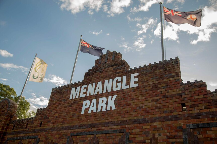 the top of a brick building which reads menangle park and has three flags atop