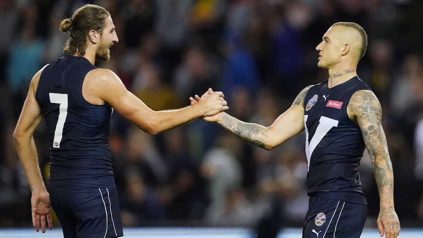 two men in dark blue AFL jumpers greet each other with hands outstretched