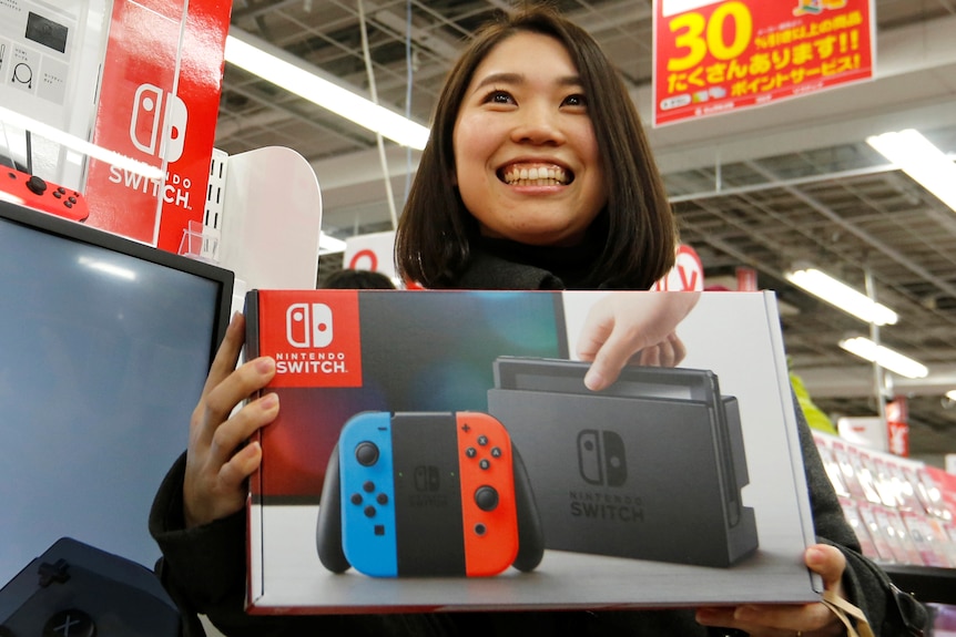 A Japanese woman smiles with her Switch console