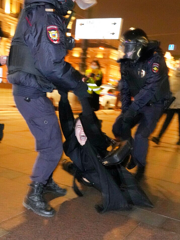 A person yells as they are carried by two police riot gear.