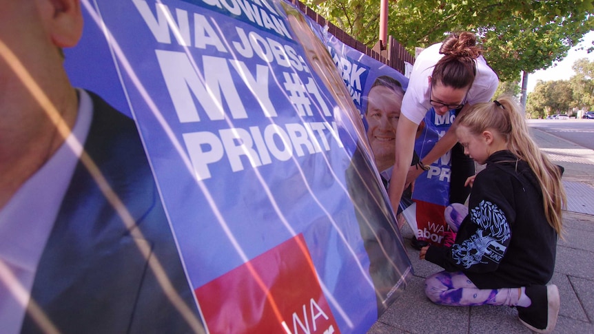 A tight shot of a woman and girl working on banners.