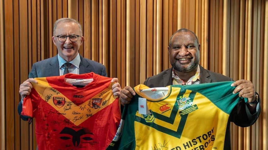 Australian and Papua New Guinea Prime Ministers hold up each countries respective signed  jerseys at the PM XIII 2022 Lang Park 