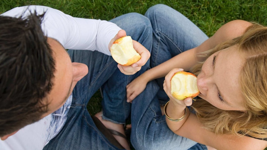 A man and woman eating apples