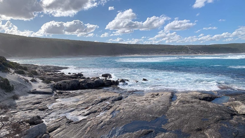 A wide shot of a bay in WA underneath a blue sky dotted with clouds.