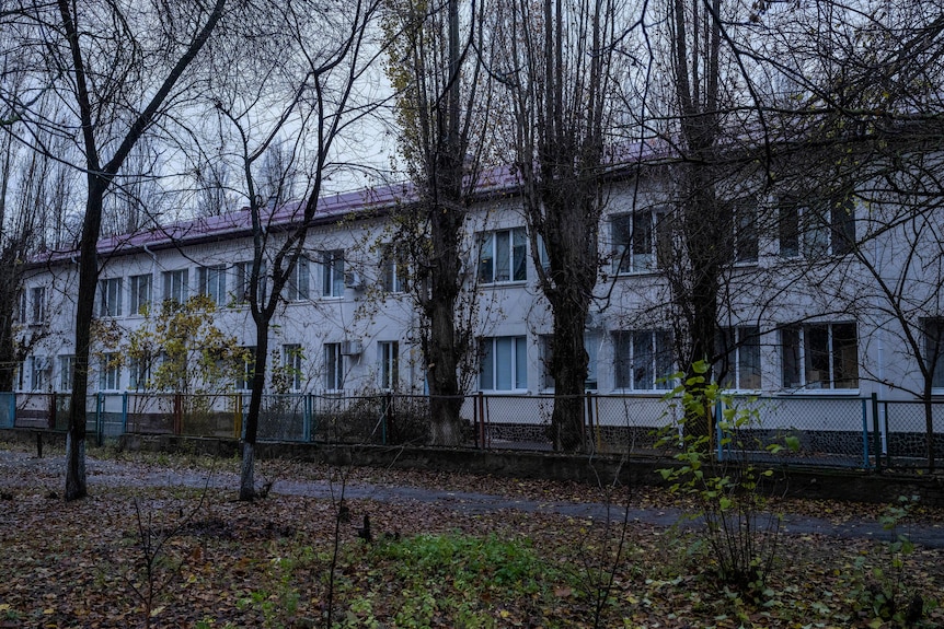 A large multi-story white building surrounded by trees, 