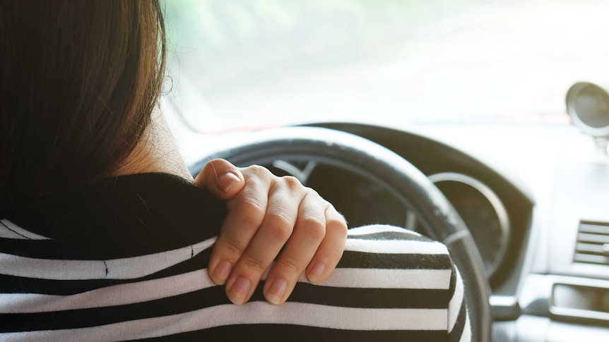 Close up woman having pain on neck and shoulder while driving car.