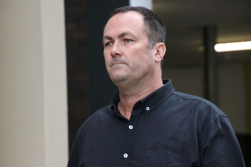 A tight mid shot of WA Police Senior Constable Grantley James Keenan walking outside a Perth court in a black shirt.