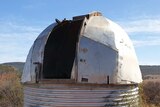 A tin dome on top of a round cylinder, form an observatory in the middle of the outback.