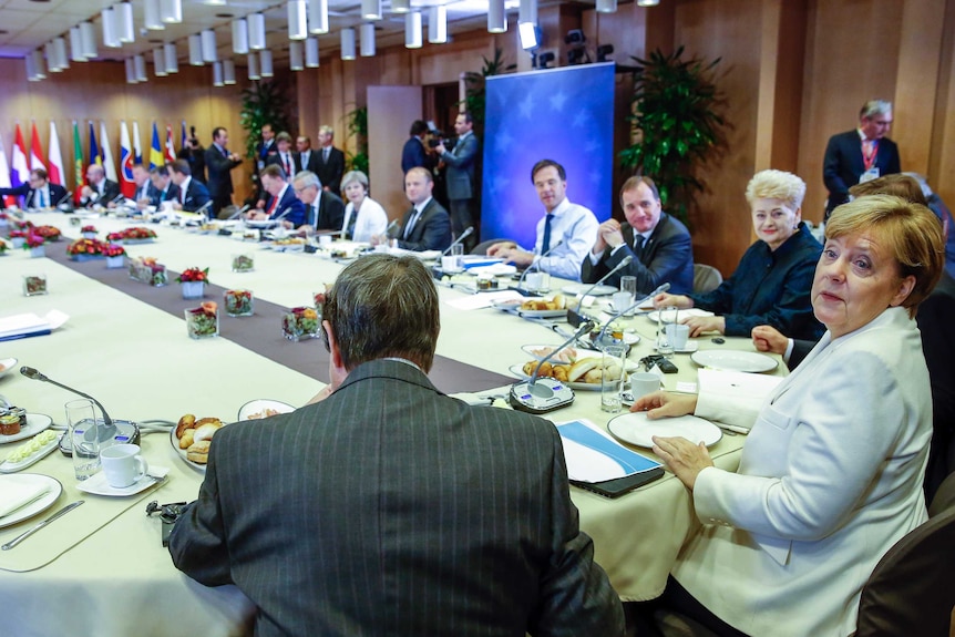 European leaders including Angela Merkel sit around a large table.