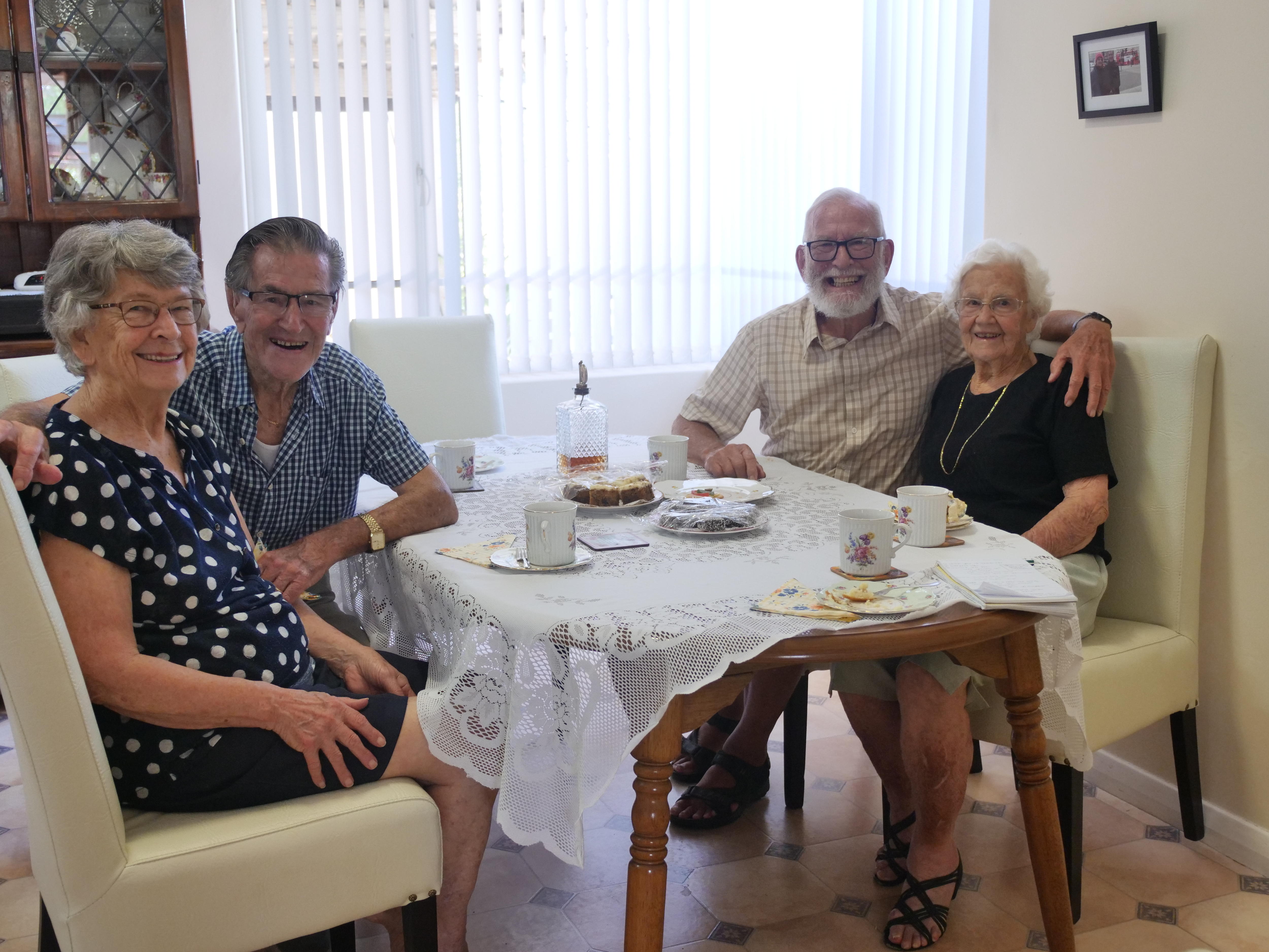 Cuatro personas se sientan a una mesa y beben té. 