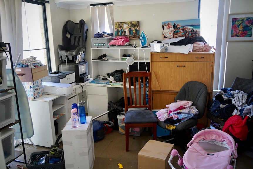 A cluttered room with clothes piled high on chairs.