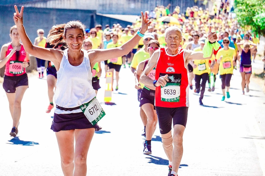 A woman does a peace sign at the front of a pack of runners