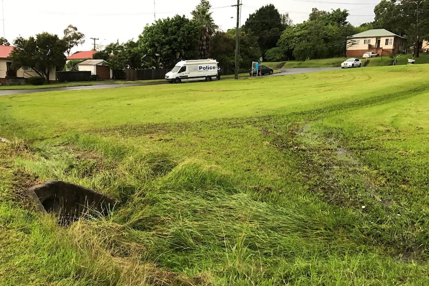 a stormwater drain with police in the background.