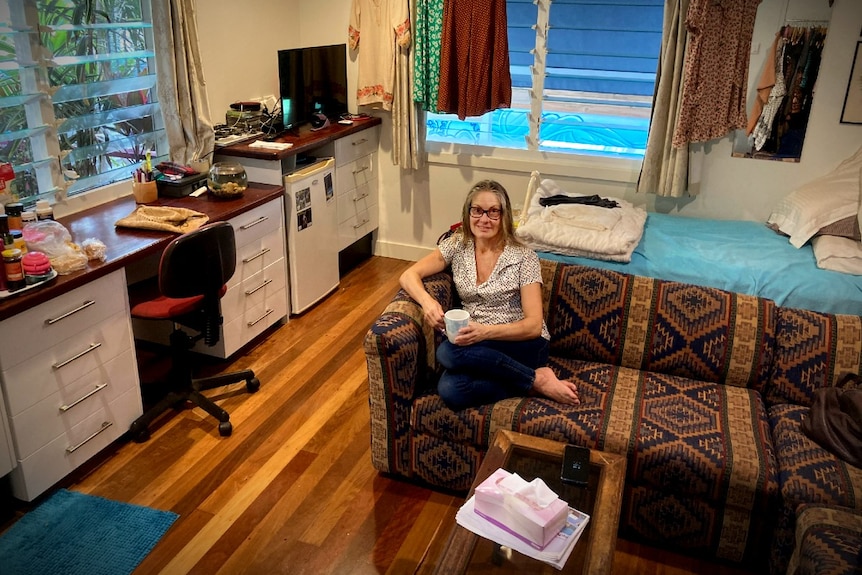 A woman in the centre of a small room, on the couch.