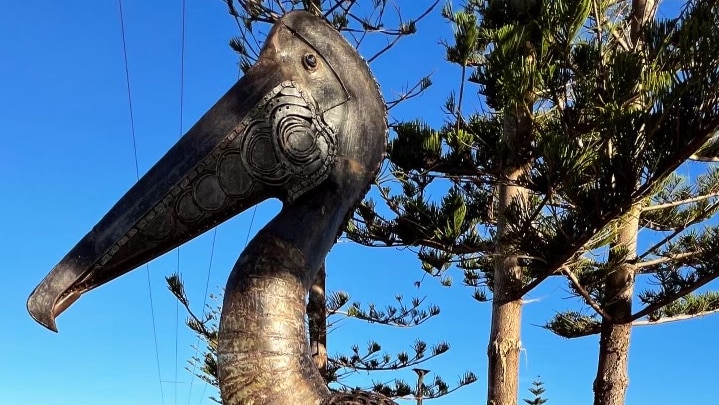 A steel pelican statue on a log