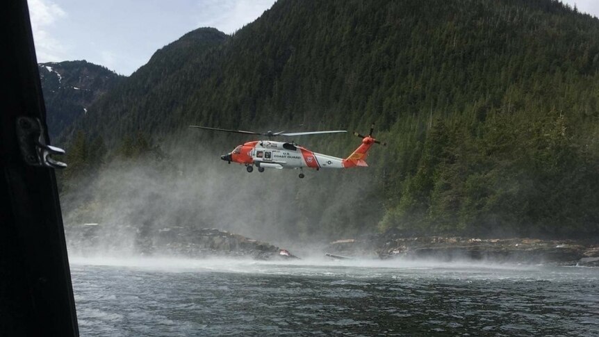 A helicopter hovers over water searching for suvivors of a seaplane crash