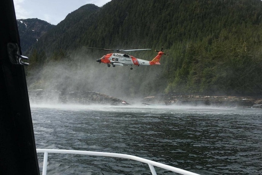 A helicopter hovers over water searching for suvivors of a seaplane crash