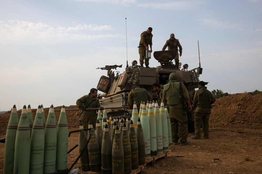 Israeli soldiers load munitions into an armoured vehicle. 