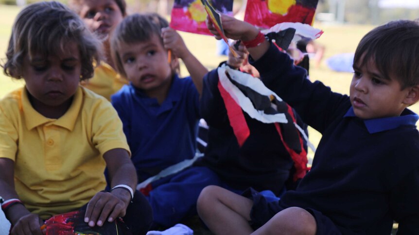 Kids hold handmade Aboriginal and Torres Strait Islander flags