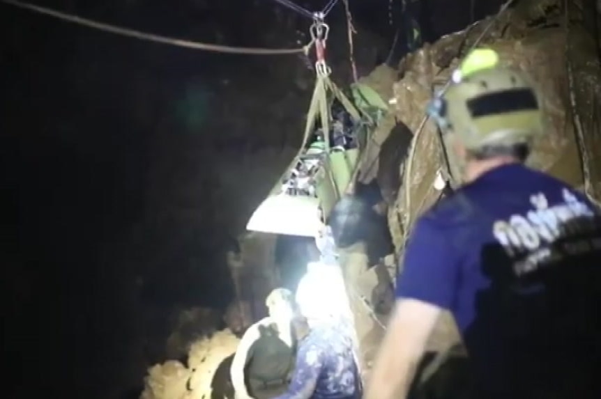Rescue workers watch on as a stretcher hangs from a rope on a pulley system in Tham Luang Cave in Thailand.