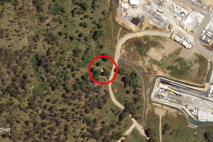 A satellite image with a red circle over a hole in the ground.