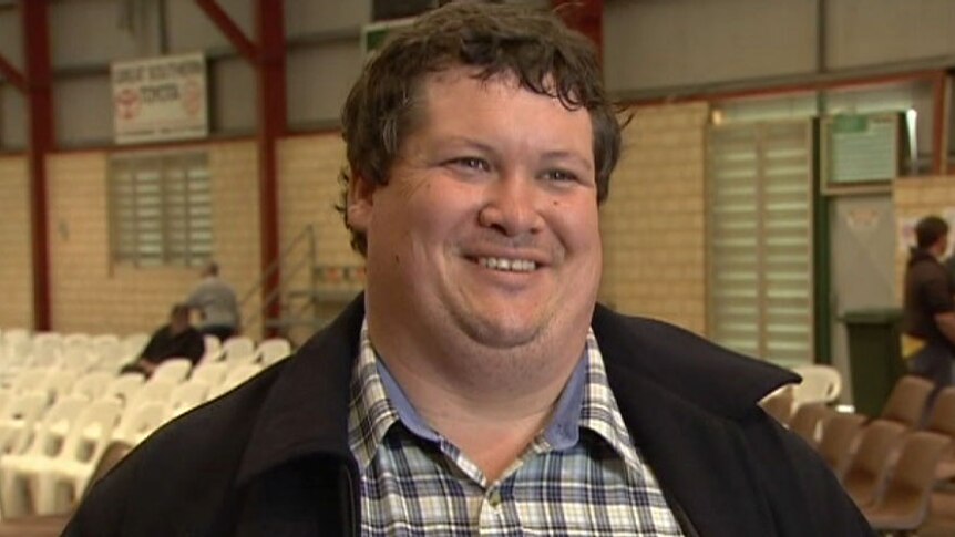 Katanning farmer Kallum Blake stands in a sports shed filled with chairs.
