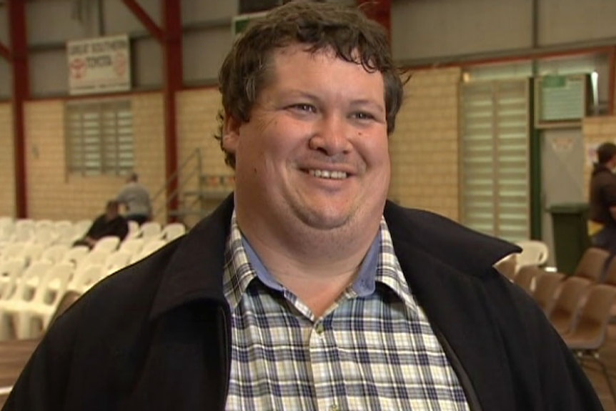 Katanning farmer Kallum Blake stands in a sports shed filled with chairs.