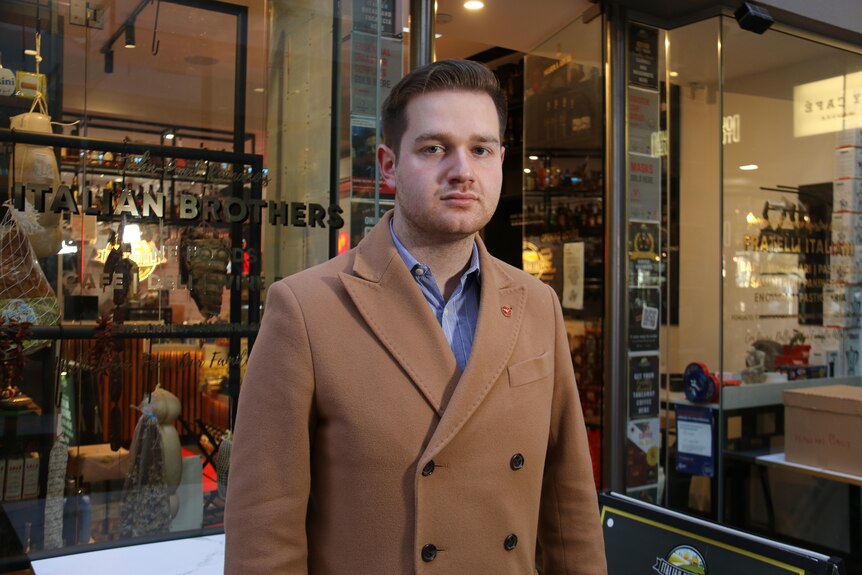 A man stands in front of a shop.