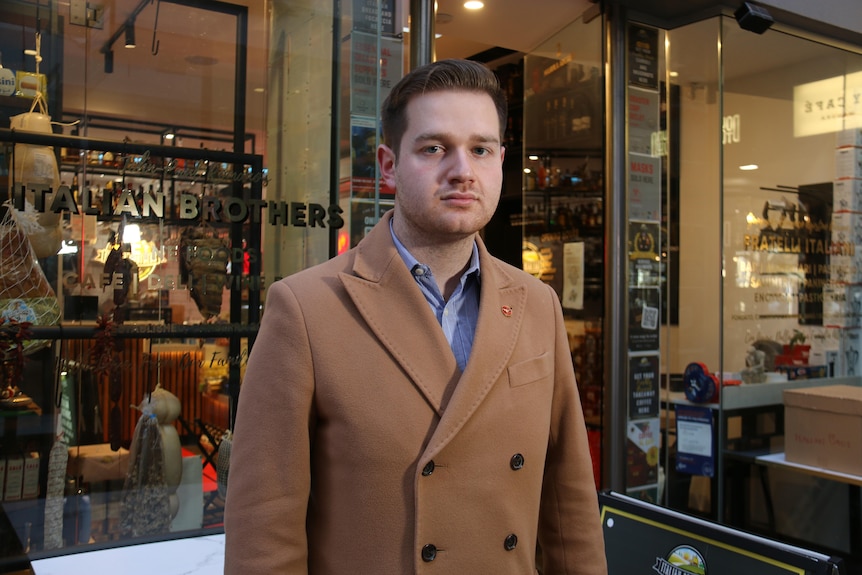 A man stands in front of a shop.