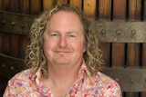 A man with shoulder-length curly blonde hair.