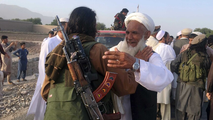 Taliban fighters gather with residents to celebrate a three-day cease fire