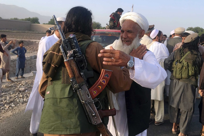 Taliban fighters gather with residents to celebrate a three-day cease fire
