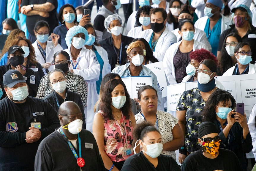 Health care workers wearing masks gather to show their solidarity with the Black Lives Matter movement.