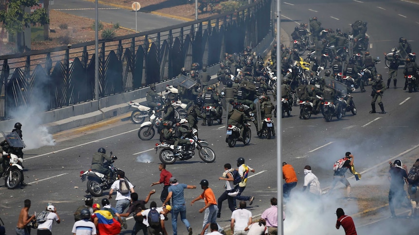 Opponents to Venezuela's President Nicolas Maduro confront loyalist Bolivarian National Guard troops firing tear gas at them